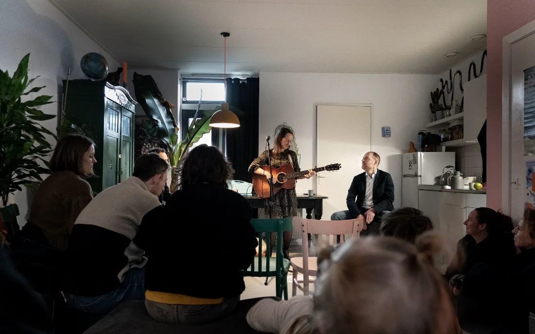 Isis zingt tussen de gasten tijdens een huiskamerconcert